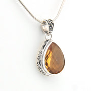 Teardrop-shaped citrine pendant on a silver chain against a white background