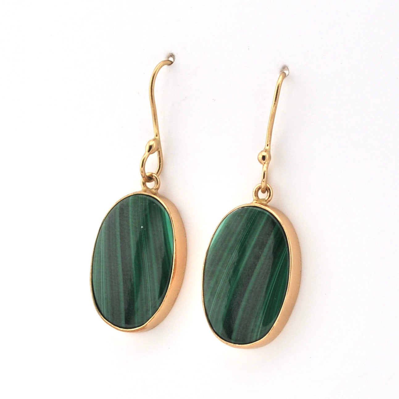 Gold earrings with green oval stones on a white background