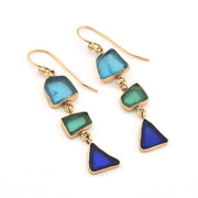Gold earrings with blue and green triangular stones on a white background