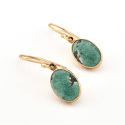 Gold earrings with green stone drops on a white background