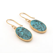Gold earrings with blue stone drops on a white background