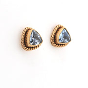 Gold earrings with light blue gemstones on a white background