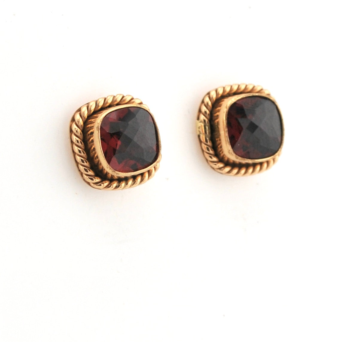 Pair of gold earrings with red gemstones on a white background