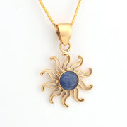 Gold sun-shaped pendant with a blue stone on a white background