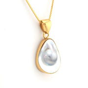 Gold pendant with a large pearl on a white background