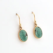 Gold earrings with green gemstones on a white background