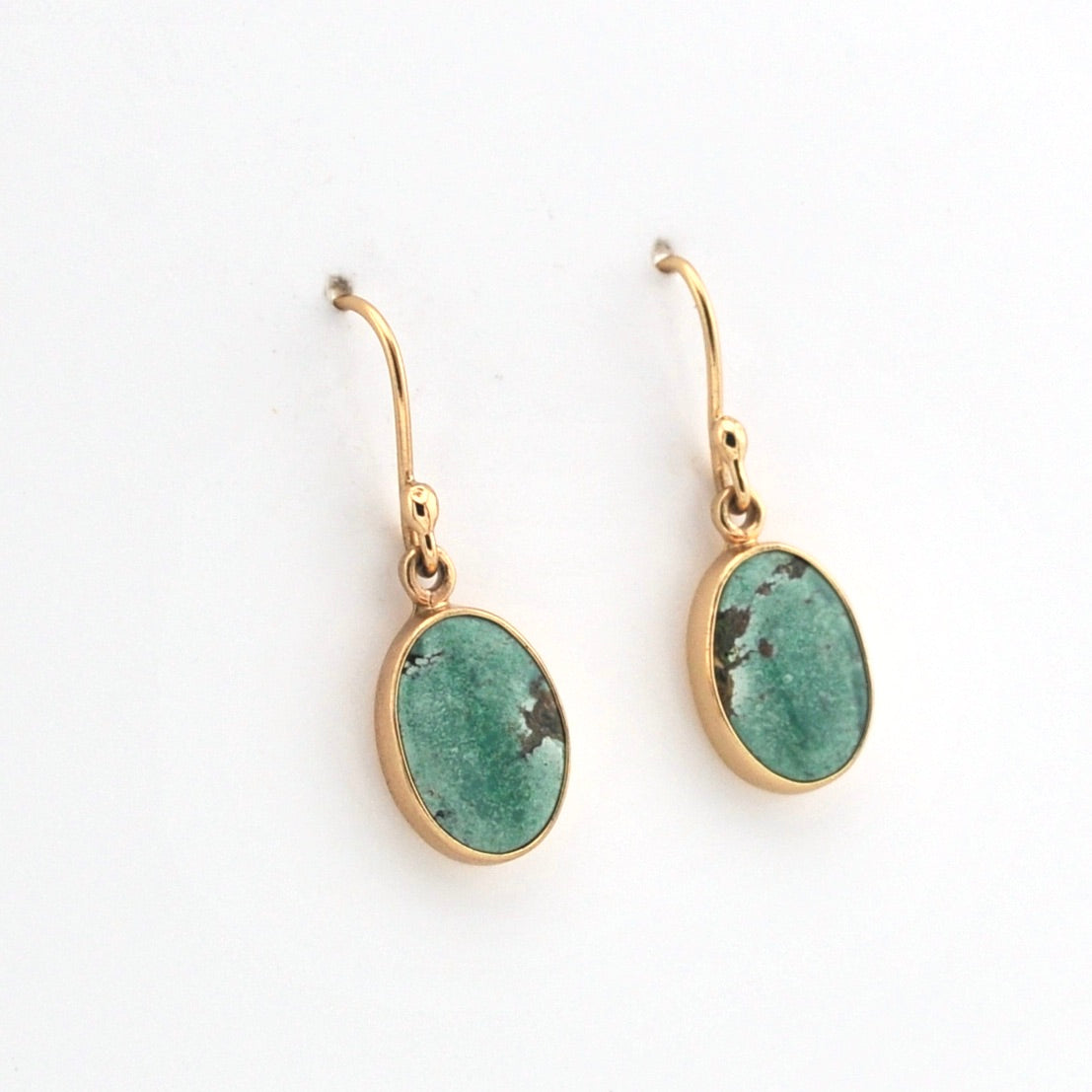 Gold earrings with green gemstones on a white background