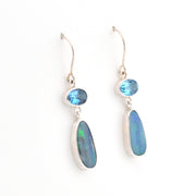 Pair of silver earrings with blue gemstones on a white background