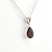Teardrop-shaped gemstone pendant on a silver chain against a white background