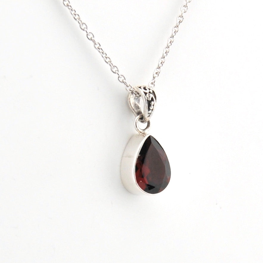 Teardrop-shaped gemstone pendant on a silver chain against a white background
