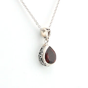 Silver necklace with a teardrop-shaped garnet pendant on a white background