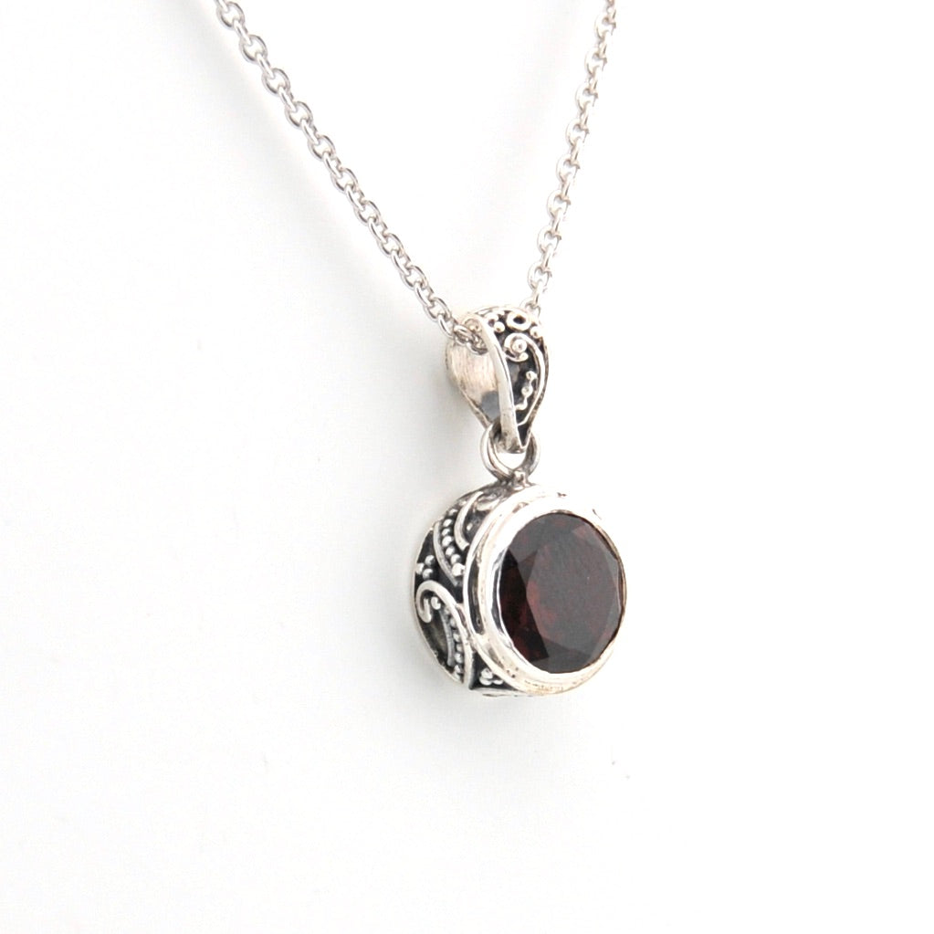Silver necklace with a garnet pendant on a white background