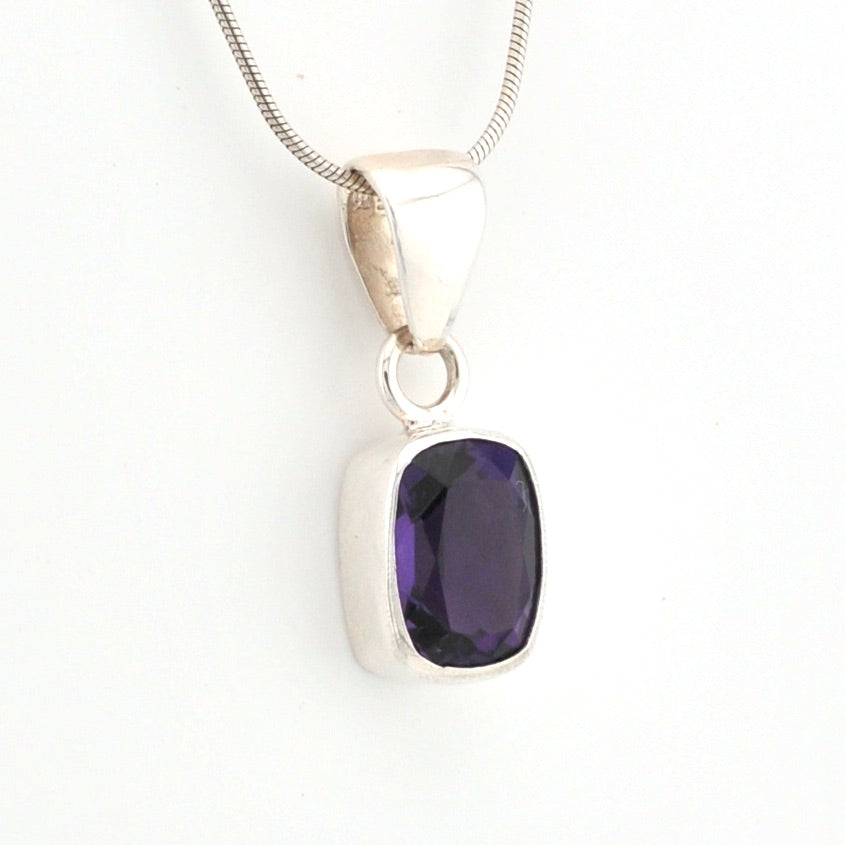 Silver pendant with a purple gemstone on a white background