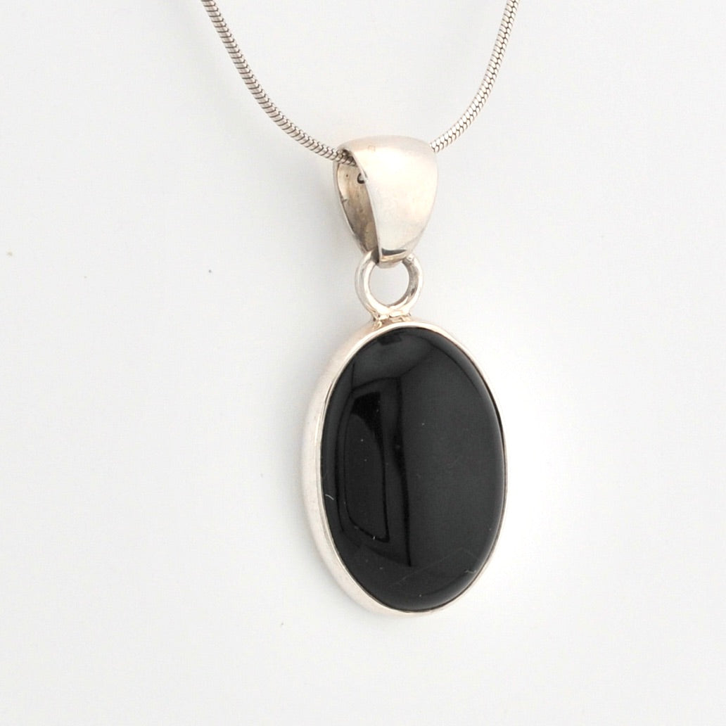 Black pendant on a silver chain against a white background