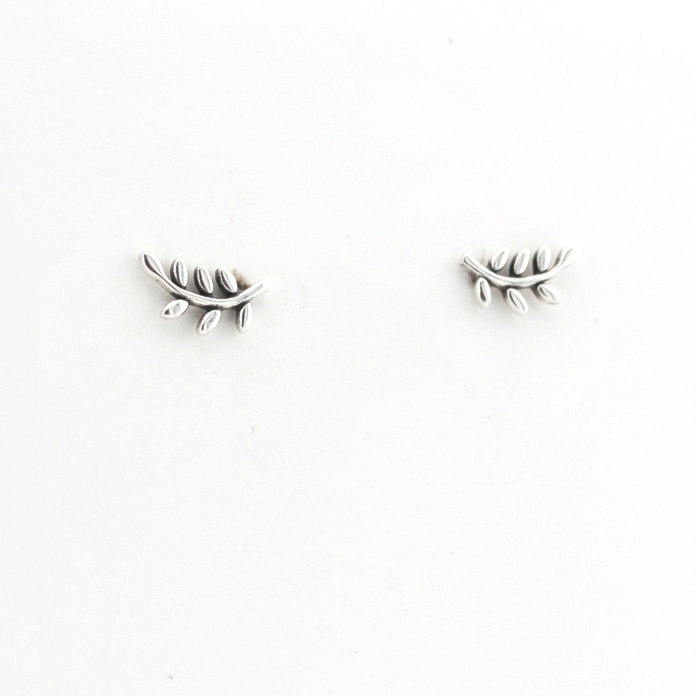 Pair of silver leaf-shaped earrings on a white background