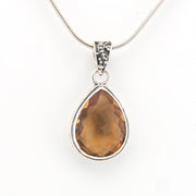 Teardrop-shaped citrine pendant on a silver chain against a white background