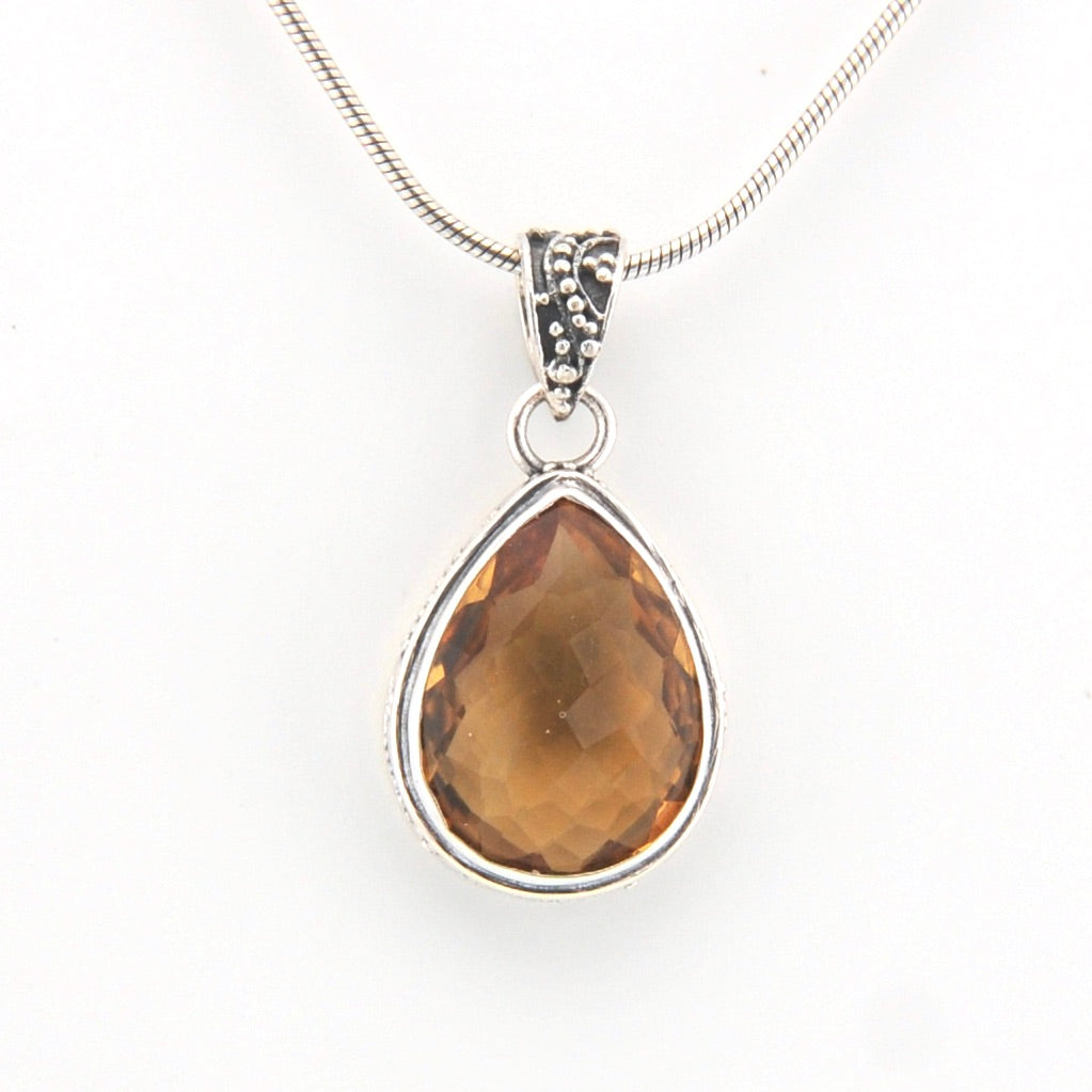 Teardrop-shaped citrine pendant on a silver chain against a white background