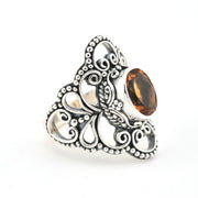 Silver ring with intricate design and a brown gemstone on a white background
