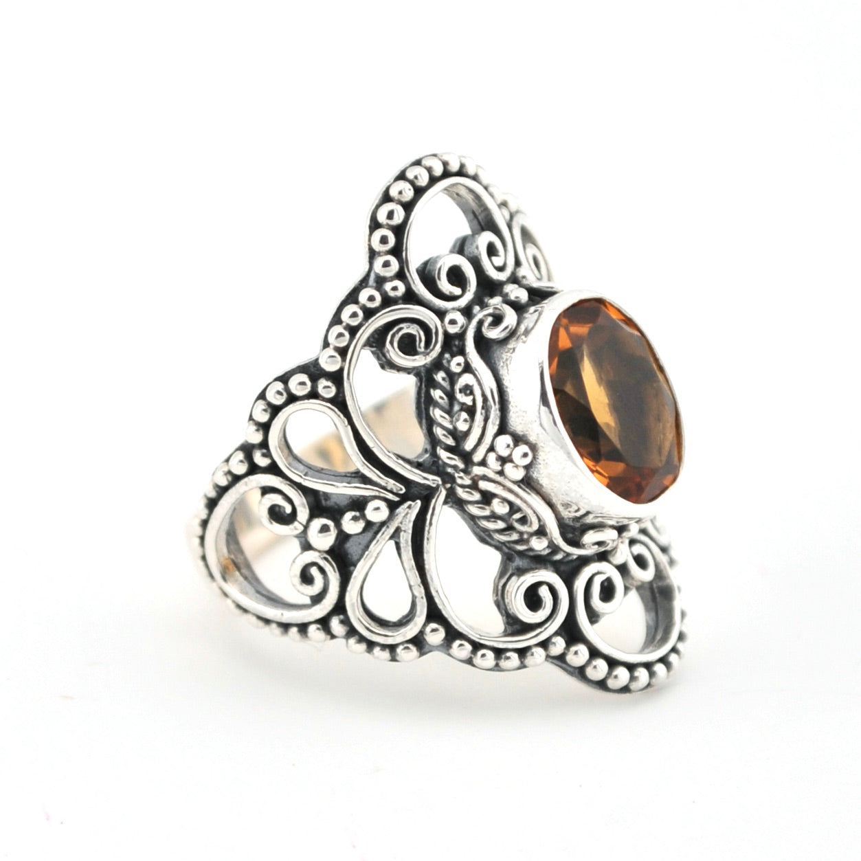Silver ring with intricate design and a brown gemstone on a white background