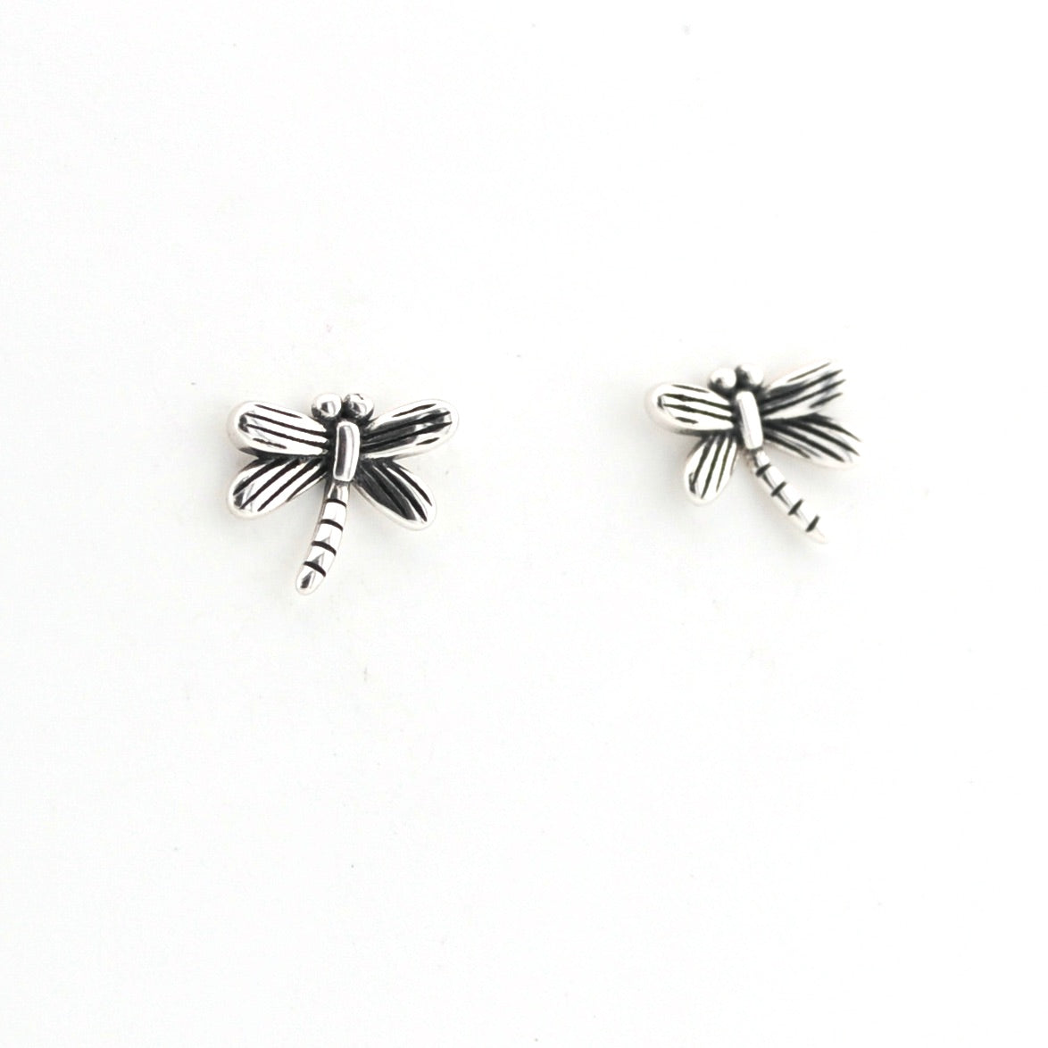 Pair of silver dragonfly-shaped earrings on a white background