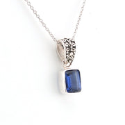 Silver pendant with a blue gemstone on a white background