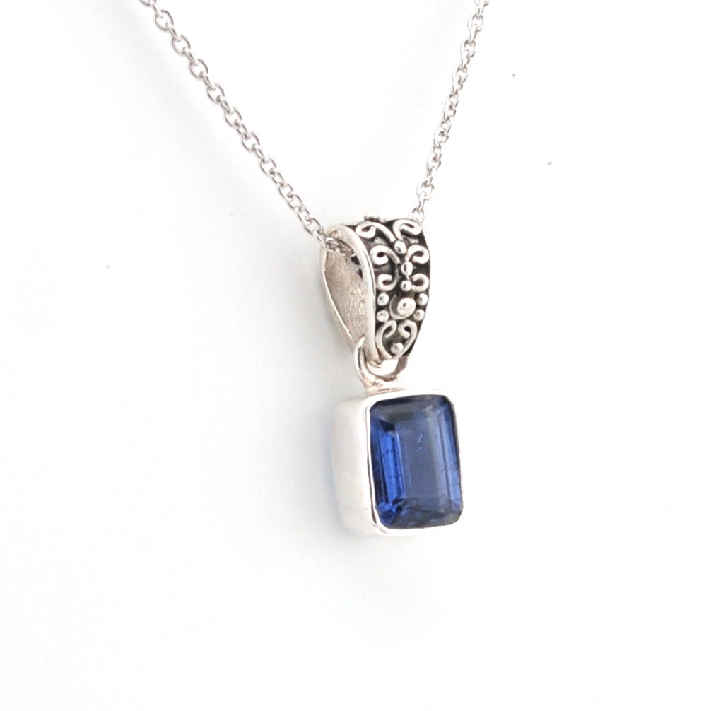 Silver pendant with a blue gemstone on a white background