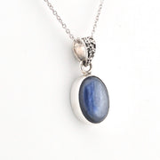 Silver pendant with a blue stone on a white background