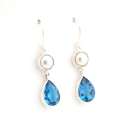 Pair of earrings with blue teardrop-shaped gemstones and pearl-like elements on a white background