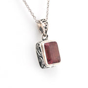 Silver pendant with a red gemstone on a white background
