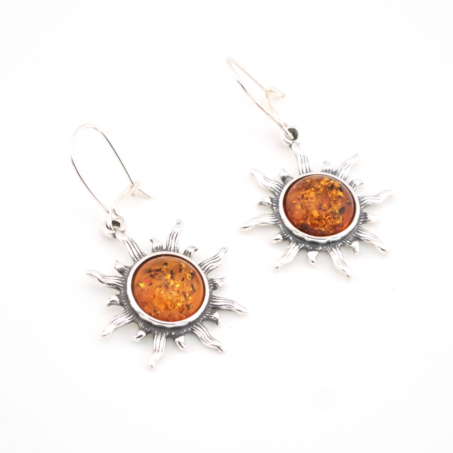 Sun-shaped earrings with amber stones on a white background