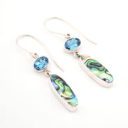 Silver earrings with blue gemstones and abalone shell on a white background