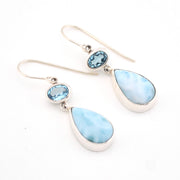 Pair of earrings with blue teardrop stones on a white background