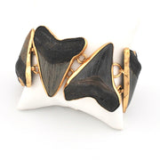 Bracelet with black shark teeth in a gold setting on a white background