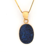 Gold necklace with a blue pendant on a white background
