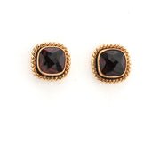 Pair of gold earrings with red gemstones on a white background