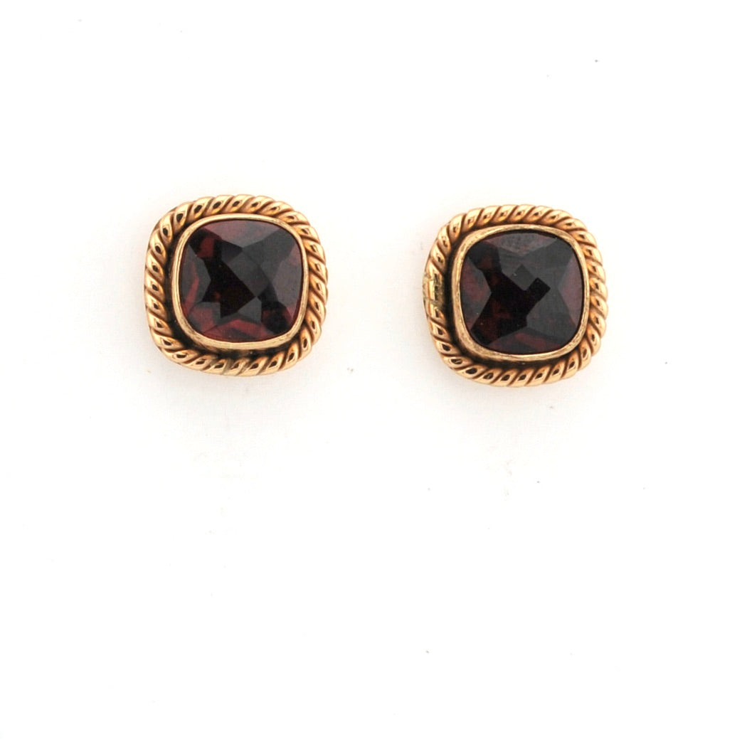 Pair of gold earrings with red gemstones on a white background