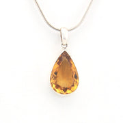 Teardrop-shaped citrine pendant on a silver chain against a white background