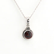 Silver necklace with a garnet pendant on a white background