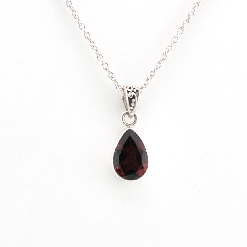 Teardrop-shaped gemstone pendant on a silver chain against a white background