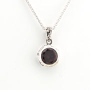 Silver necklace with a round garnet pendant on a white background