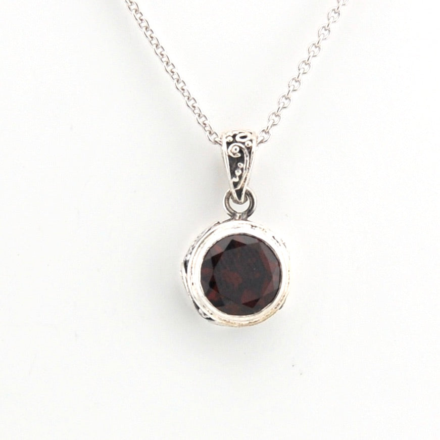 Silver necklace with a round garnet pendant on a white background