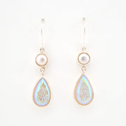 Teardrop-shaped earrings with pearl-like tops on a white background