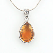 Teardrop-shaped citrine pendant on a silver chain against a white background