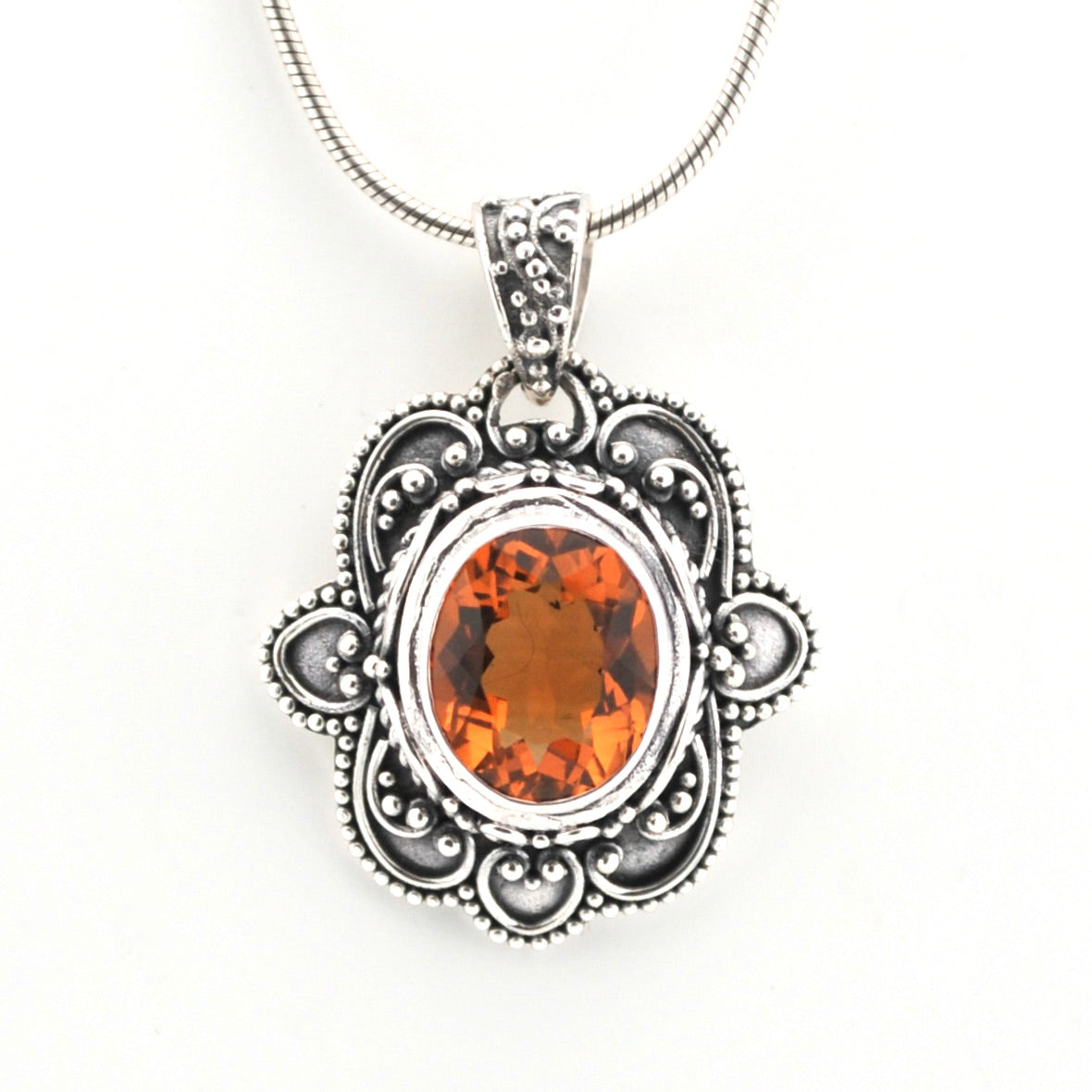 Silver pendant with an orange gemstone on a white background