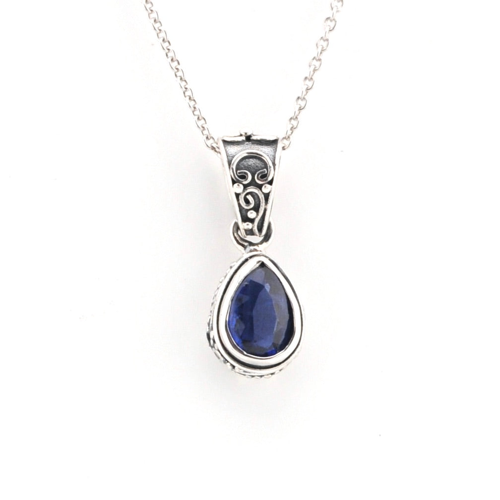 Silver pendant with a blue gemstone on a white background