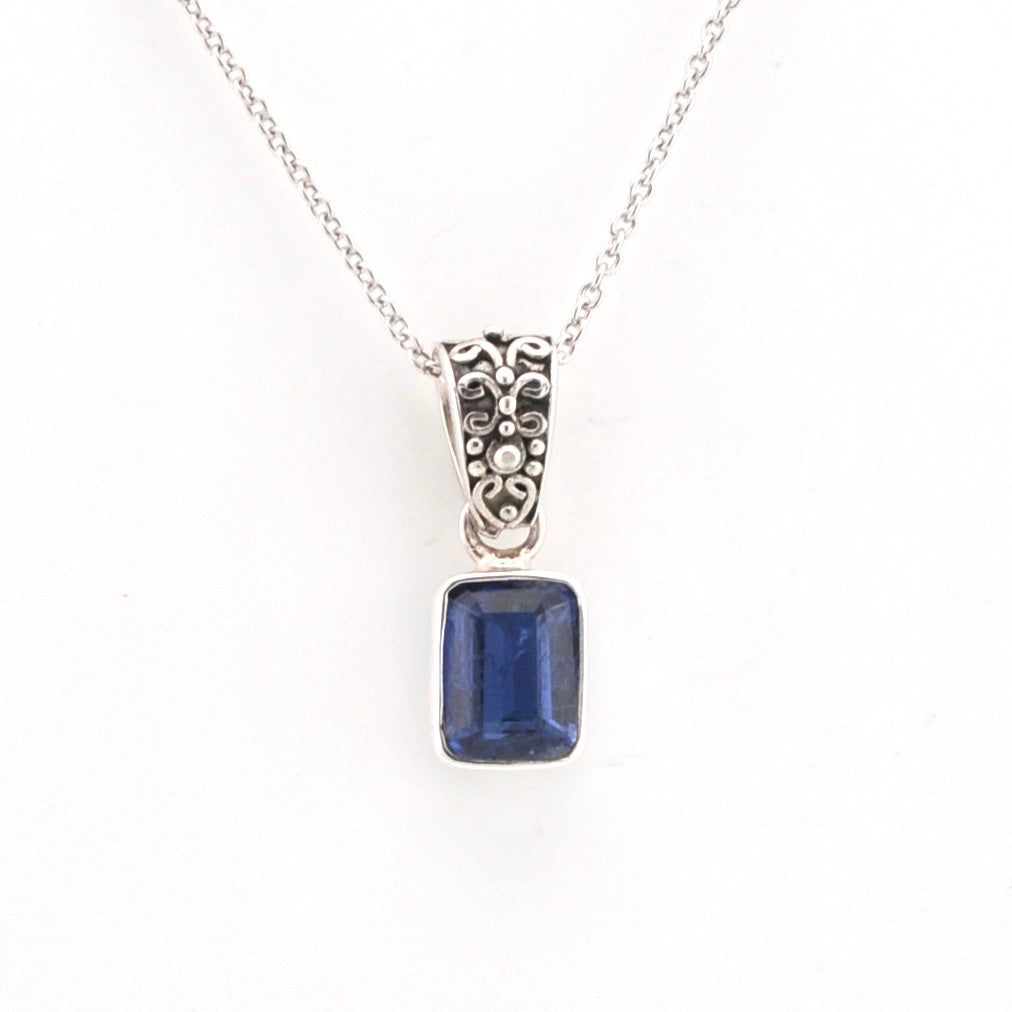 Silver necklace with a blue gemstone pendant on a white background