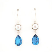 Pair of earrings with blue teardrop-shaped gemstones and pearl on a white background