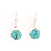 Turquoise round earrings on silver hooks against a white background