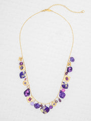 Necklace with purple and gold beads on a light gray background