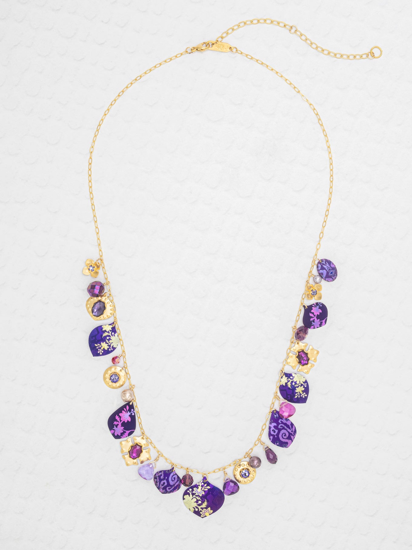 Necklace with purple and gold beads on a light gray background